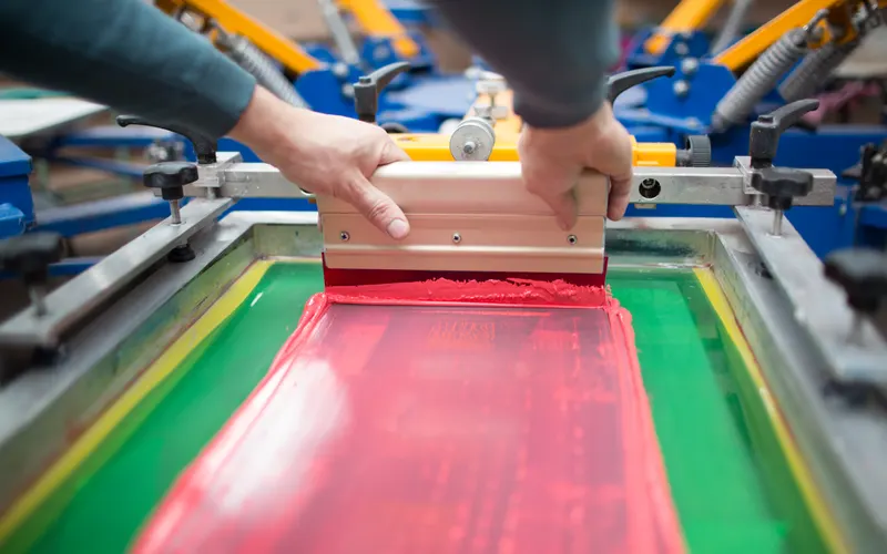 Squeegee pulling ink across a screen printing frame